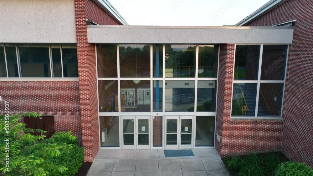 Aerial pullback of brick elementary school in America. View from exterior shows lobby inside of American school on spring day. No people. Aerial pullback of brick elementary school in America. View from exterior shows lobby inside of American school on spring day. No people.