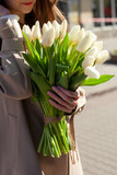 Cropped girl holding bouquet of white tulips. Womans hands holding a huge blossoming bouquet of fresh spring flowers. Concept of gift for the Mother's day, Valentine's day, March 8 women's day.
