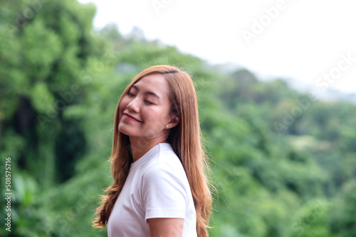 Portrait image of a young woman closed her eyes and enjoy a beautiful mountains and nature view