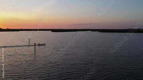 Aerial view around a boat driving across the sea, sunset on the coast of South Florida - circling, drone shot photo