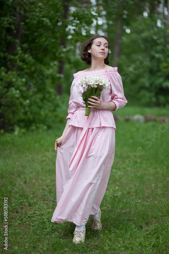 A girl in a pink dress walks with a bouquet of flowers. Bouquet of anemones. The bride's bouquet.