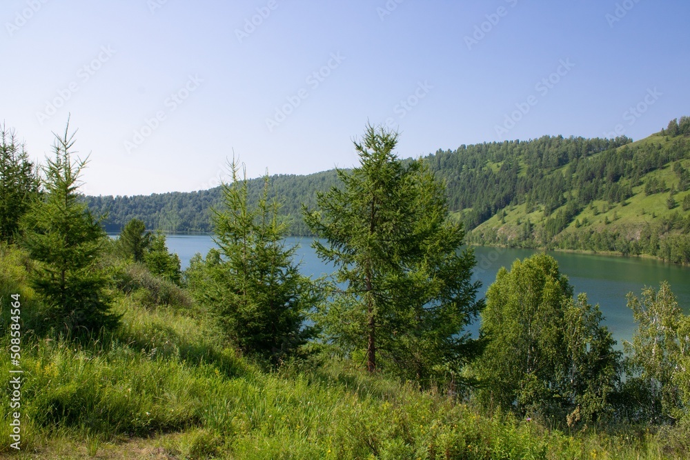 Picturesque lake surrounded by mountains with green grass and trees.