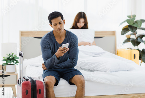 Fototapeta Asian upset stressed depressed frowning face young husband having problem fighting arguing with sad wife who sitting on bed