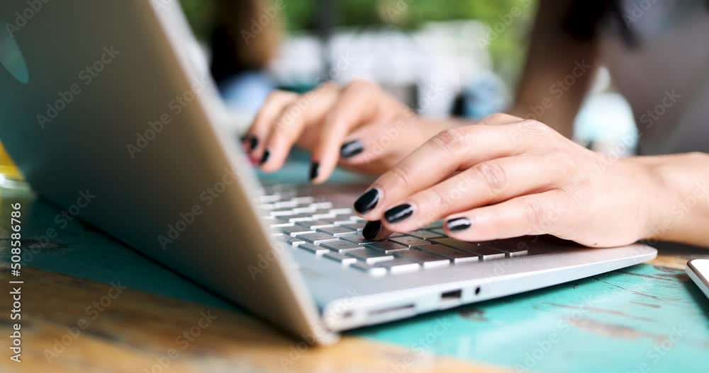 Hands with black nail polish typing on laptop Hands with black nail polish typing on laptop
