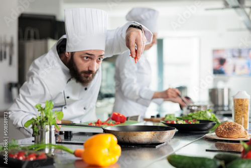 Food industry worker cooking delicious gourmet dish for dinner service at restaurant. Skilled and confident head chef chopping organic and fresh red bell pepper while preparing garnish.