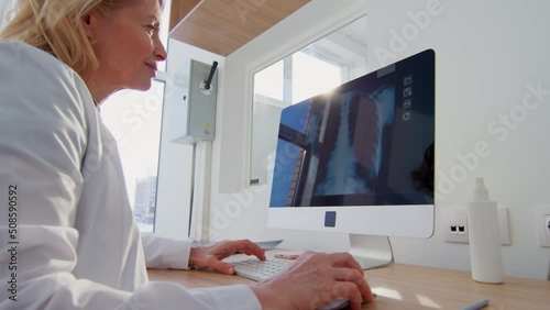 Doctor sitting at desk looking at patient's x-ray photo
