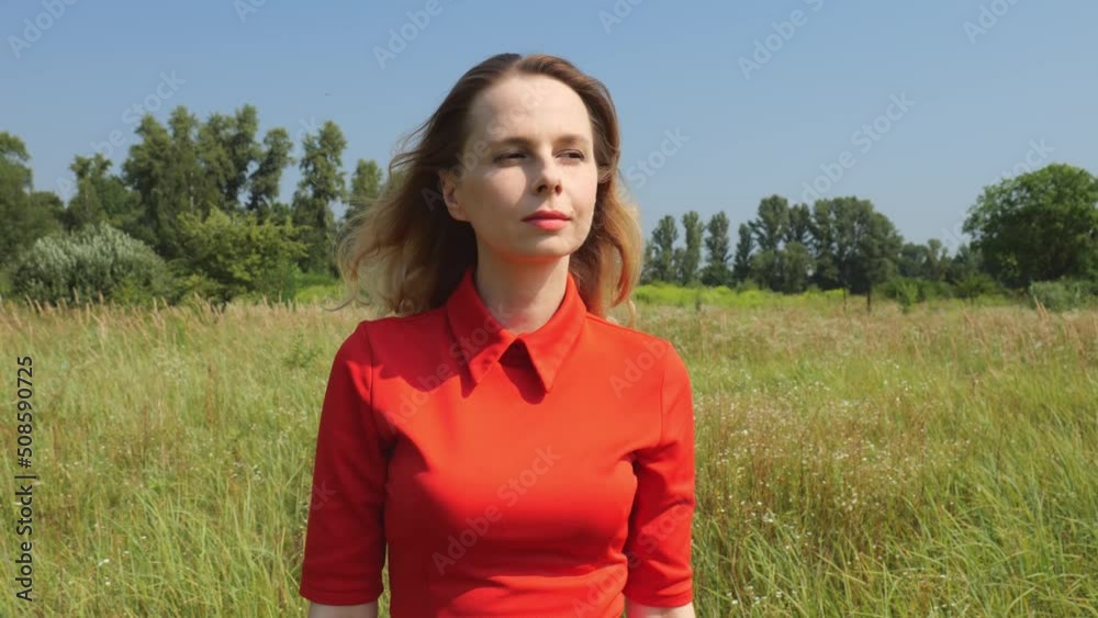 Portrait of a forty-year-old woman in a red dress in nature.Slow motion. Woman walking on the field Portrait of a forty-year-old woman in a red dress in nature.Slow motion. Woman walking on the field
