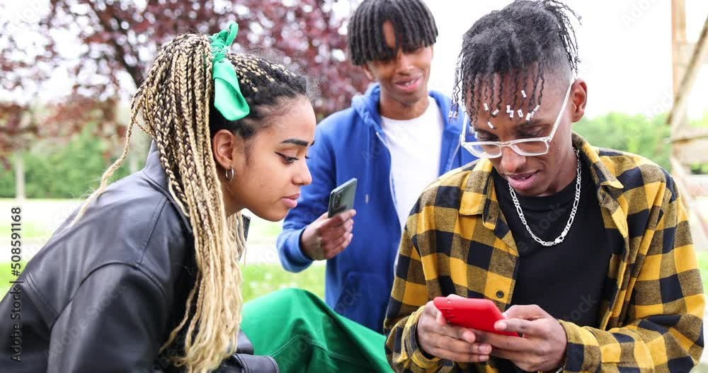 Cool friends sitting in the city watching smartphone together Cool friends sitting in the city watching smartphone together