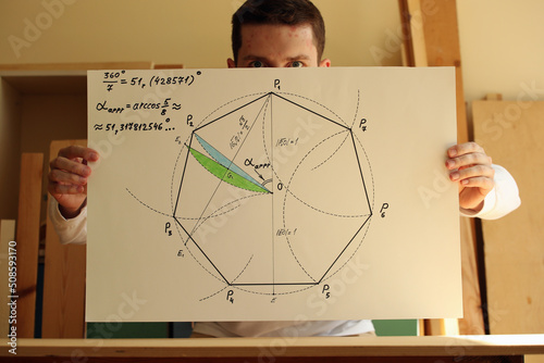 Young mathematician and designer and his drawing regular heptagon with green and blue colours on the paper in hands. Photo was taken 14 May 2022 year, MSK time in Russia. photo
