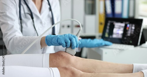 Orthopedic doctor makes ultrasound examination of patient knee in office photo