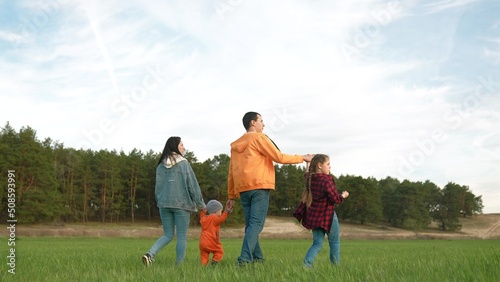 people in the park. happy family a walk at sunset. mom dad and daughter walk holding hands in the park. happy family kid dream concept. parents and fun baby walking forest park life