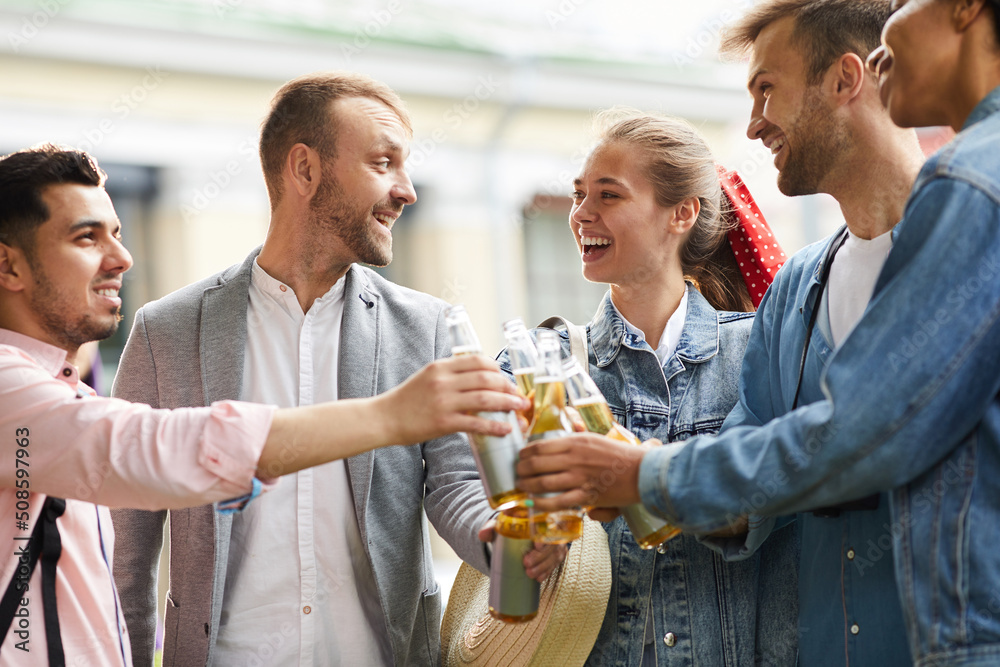 Group of excited young friends in casual clothing standing together and having fun with beer Group of excited young friends in casual clothing standing together and having fun with beer