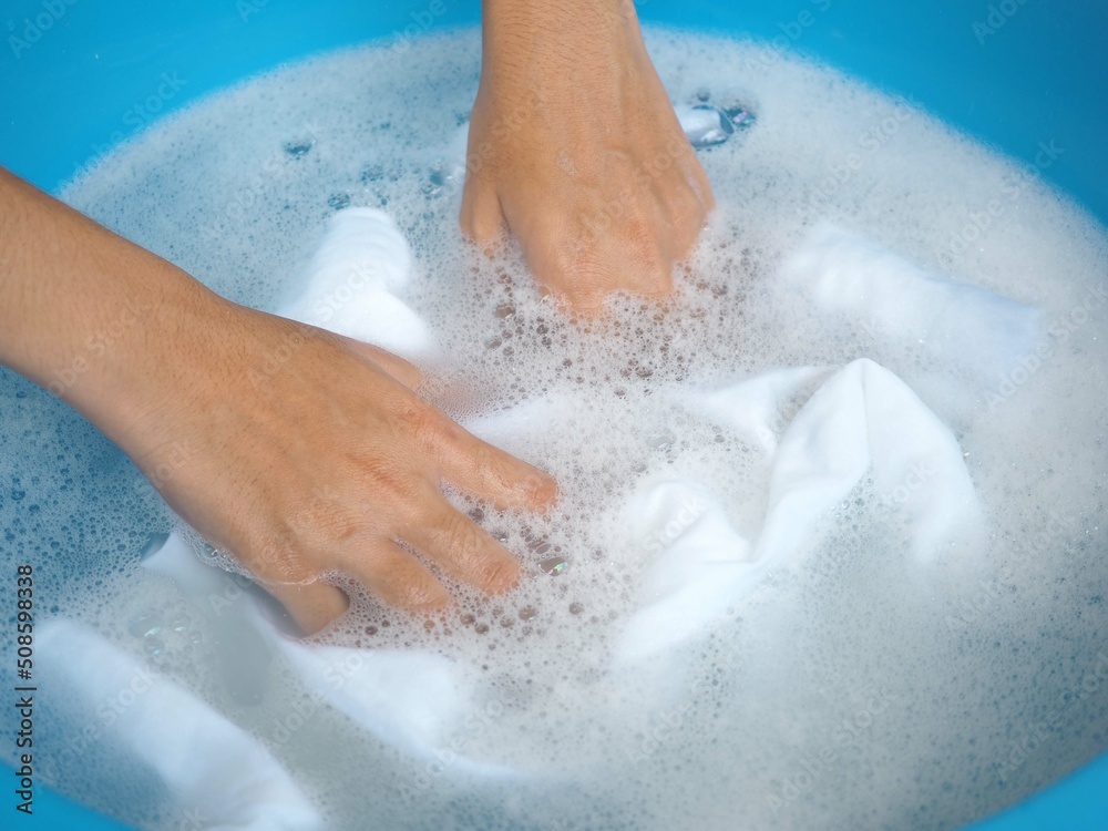 Woman washes clothes by hand in detergent water. top view photo, blurred.