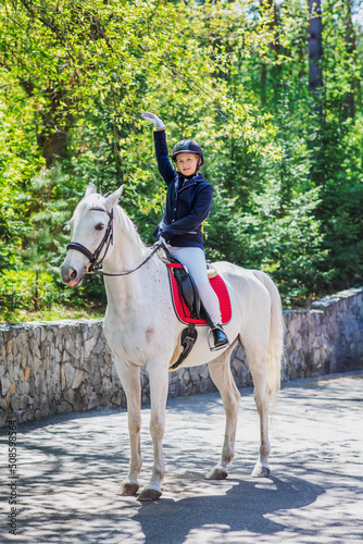 Jacquey girl with her favorite white horse for a walk in the spring forest. Preparing for the jumps. Communication with animals in nature. 