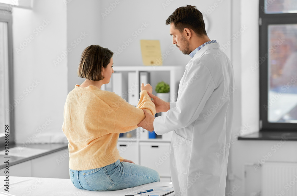 medicine, healthcare and people concept - male doctor with clipboard talking to woman showing her sore arm patient at hospital medicine, healthcare and people concept - male doctor with clipboard talking to woman showing her sore arm patient at hospital