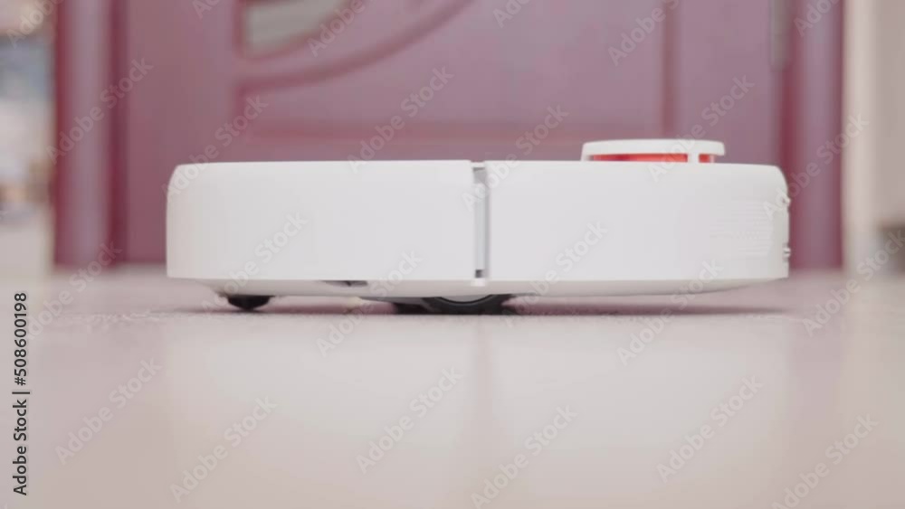 Robot vacuum cleaner vacuuming the floor in the room. Smart home with automated devices that simplify life. A smart vacuum cleaner cleans the floor. High quality FullHD footage Robot vacuum cleaner vacuuming the floor in the room. Smart home with automated devices that simplify life. A smart vacuum cleaner cleans the floor. High quality FullHD footage