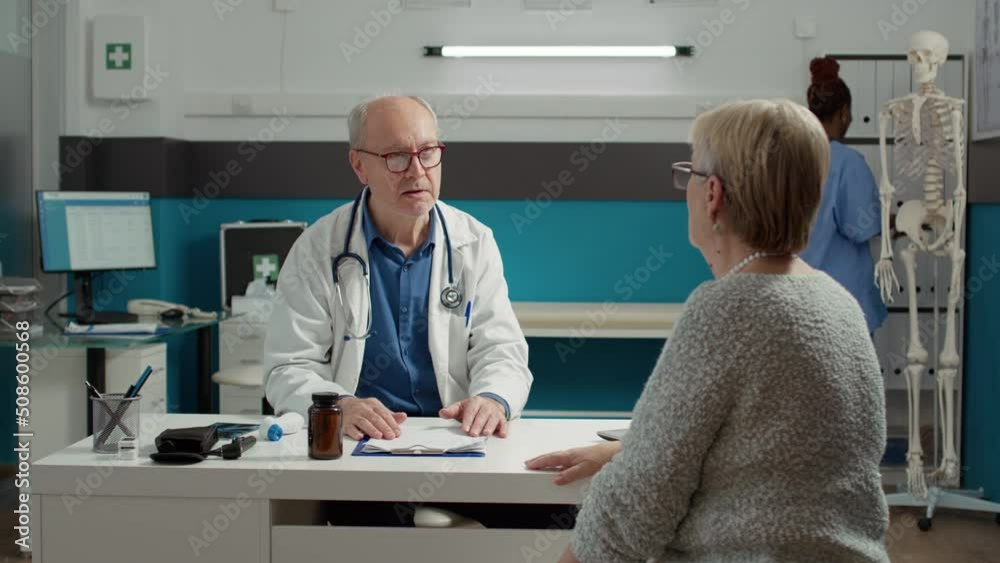 Medic and retired patient talking about recovery at checkup visit, examining person to give prescription medicine and treatment. Senior doctor and woman doing illness consultation. Medic and retired patient talking about recovery at checkup visit, examining person to give prescription medicine and treatment. Senior doctor and woman doing illness consultation.