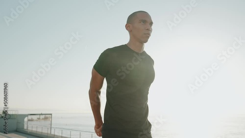 Handsome bald sportsman wearing black t-shirt does hands warm-up outdoors in the morning photo