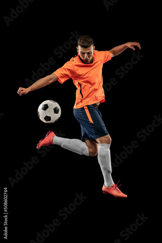 Studio shot of professional male football soccer player in motion isolated on dark background. Concept of sport, goals, competition, hobby, achievements © master1305