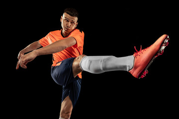 Dynamic portrait of professional male football soccer player in motion isolated on dark background. Concept of sport, goals, competition, hobby, achievements