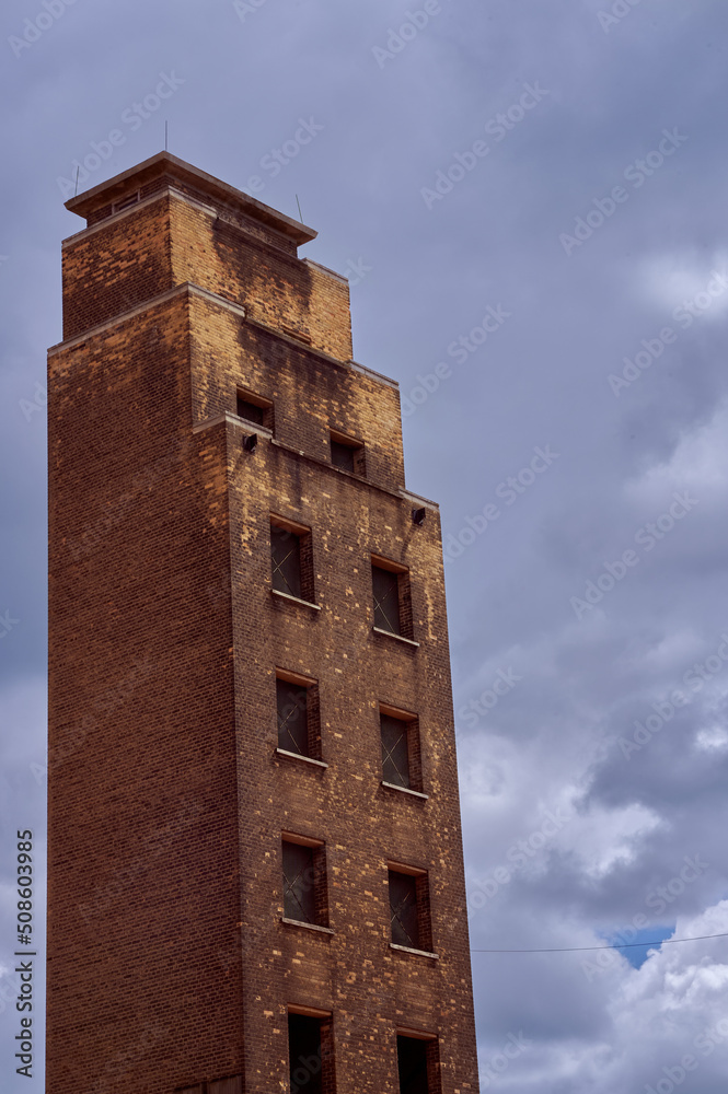 old red brick fire service drill tower or training tower against overcast sky