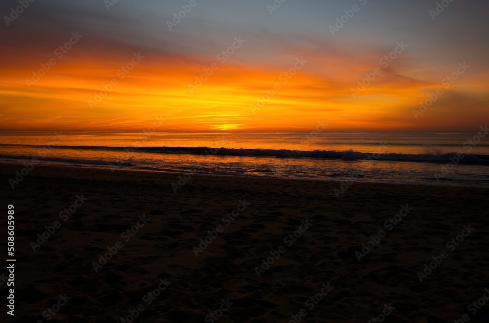 Orange sunset at the ocean, empty beach, evening time