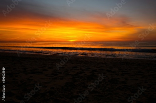 Orange sunset at the ocean, empty beach, evening time
