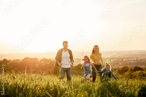 Running of family with two daughters at the meadow