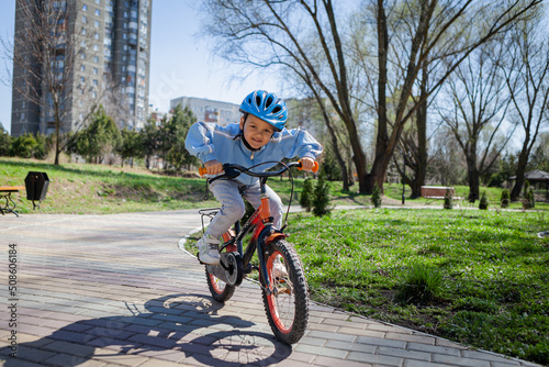 Happy kid boy of 5 years having fun in spring park with a bicycle on beautiful fall day. 