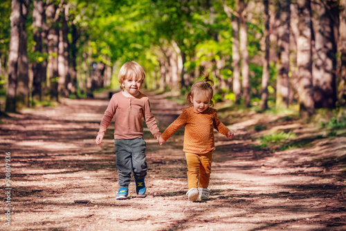 Boy and a girl walk holding hands on an alley in the park