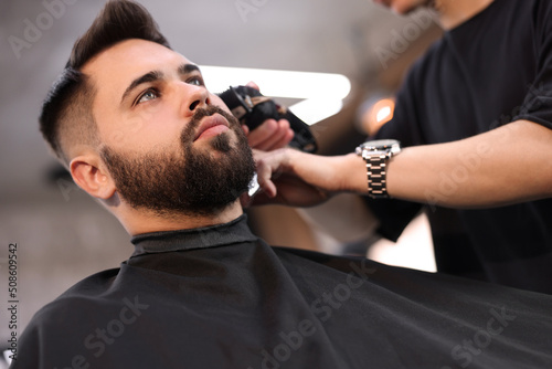 Professional hairdresser working with client in barbershop, low angle view