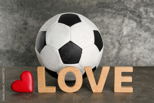 Soccer ball, heart and word Love on grey table