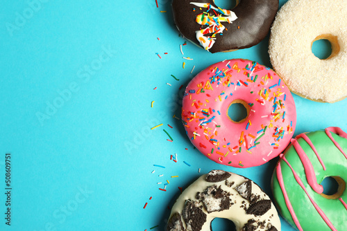 Fototapeta Different delicious glazed doughnuts on light blue background, flat lay