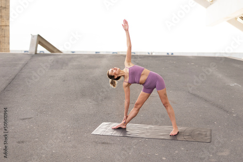 Beautiful young woman practising yoga outside. Fit woman doing yoga stretching exercises