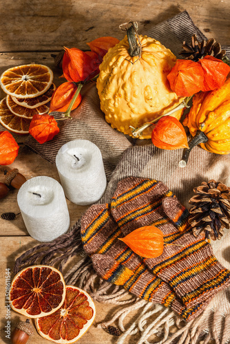 Autumn cozy composition. Scarf  warm mittens  candles  pumpkins  fall decor. Wooden background