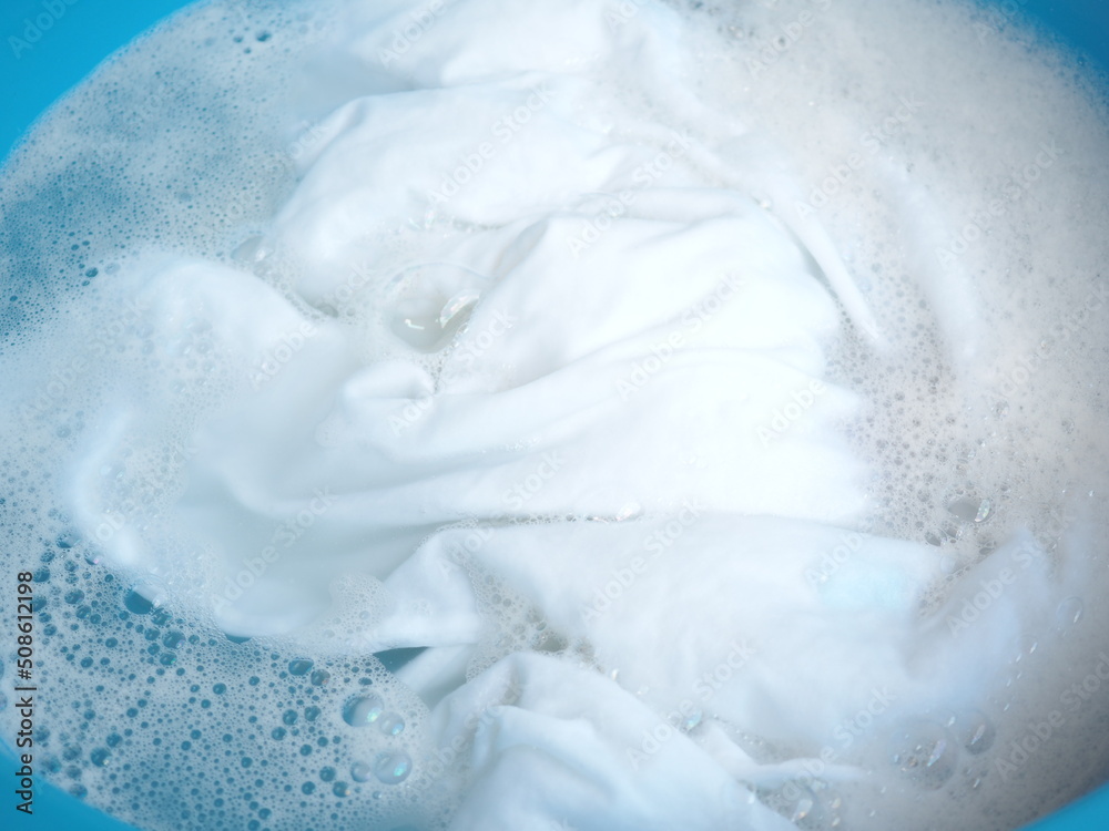 Shirt washing with detergent bubble in wash tub. top view photo, blurred. Shirt washing with detergent bubble in wash tub. top view photo, blurred.