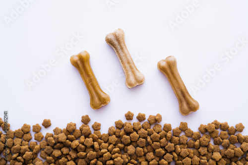 top view of bone shaped dog treats near pet food.