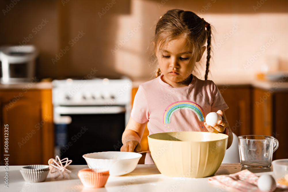 Cute little blonde girl cooking dough in kitchen at home Cute little blonde girl cooking dough in kitchen at home