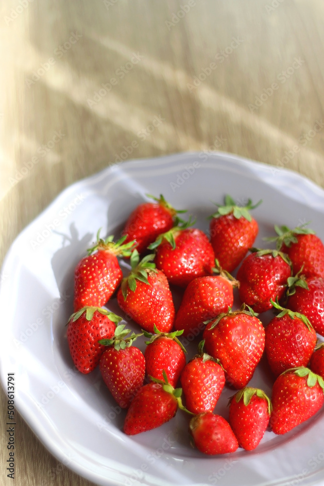 Lilac plate full of fresh strawberries on wooden table. Selective focus. Lilac plate full of fresh strawberries on wooden table. Selective focus.