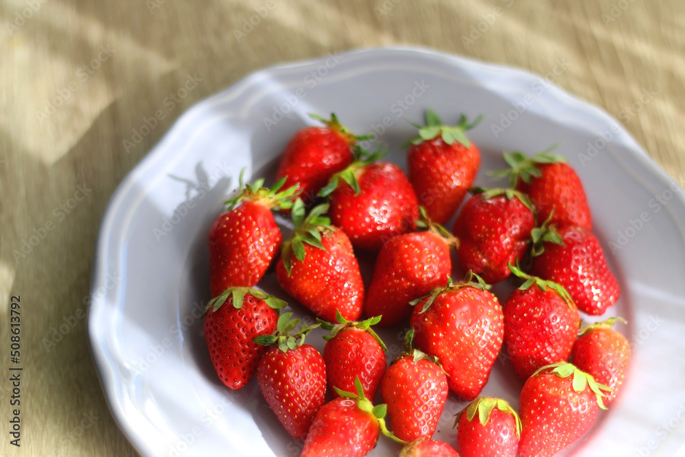 Lilac plate full of fresh strawberries on wooden table. Selective focus. Lilac plate full of fresh strawberries on wooden table. Selective focus.