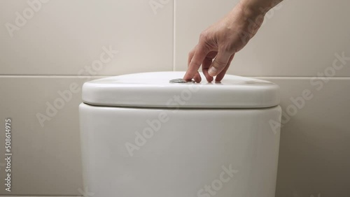 4k video footage of a hand pressing a button to flush water in toilet photo
