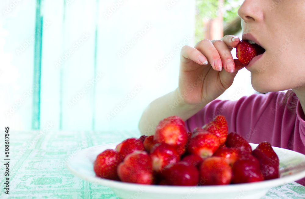 The girl holds strawberries in her hand, summer sweets, the girl eats strawberries The girl holds strawberries in her hand, summer sweets, the girl eats strawberries