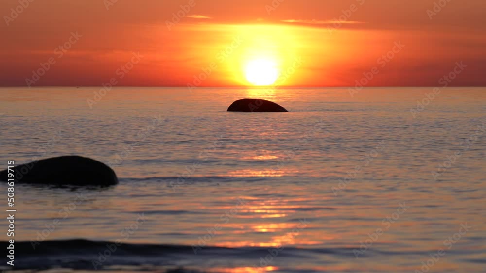 Calm water surface during beautiful orange sunset. Big stones in water. Insects flying. Calm water surface during beautiful orange sunset. Big stones in water. Insects flying.