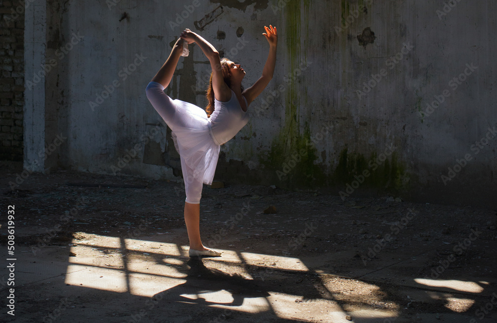 Young ballerina in white tutu dancing and jumping in abandoned building on a sunny summer day Young ballerina in white tutu dancing and jumping in abandoned building on a sunny summer day