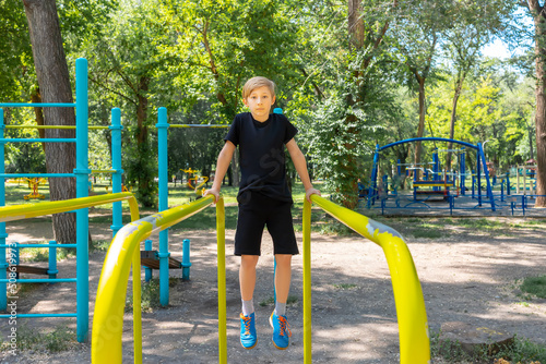 athlete boy prepared for exercises on gymnastic bars in the park