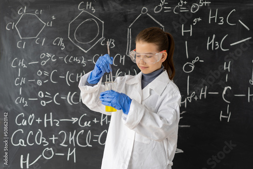 Little girl scientist examining flask with chemical reagent. Schoolgirl making experiment in chemistry class. children working in a chemistry lesson. Education