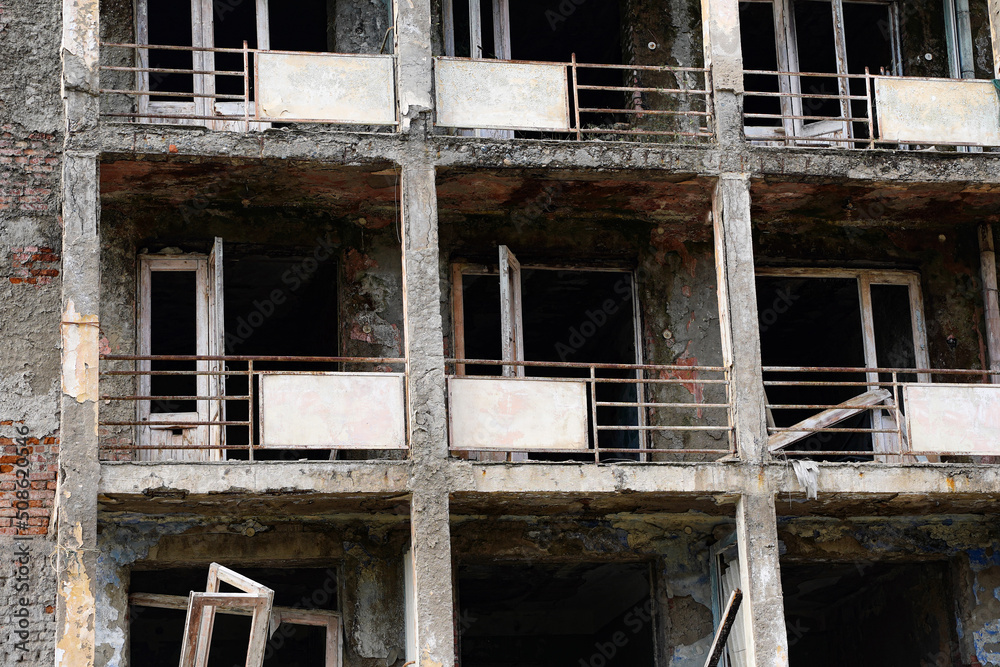 Close up fragment of an abandoned residential multi-storey building. Destroyed balconies, lack of windows and doors Close up fragment of an abandoned residential multi-storey building. Destroyed balconies, lack of windows and doors