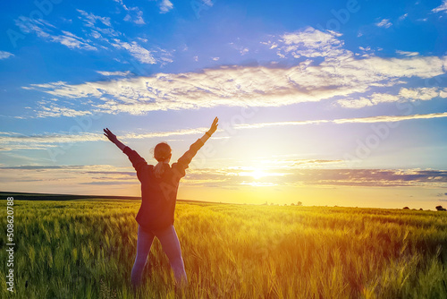 Free young woman raising arms to golden sunset. Freedom and success concept,relaxing and enjoying nature