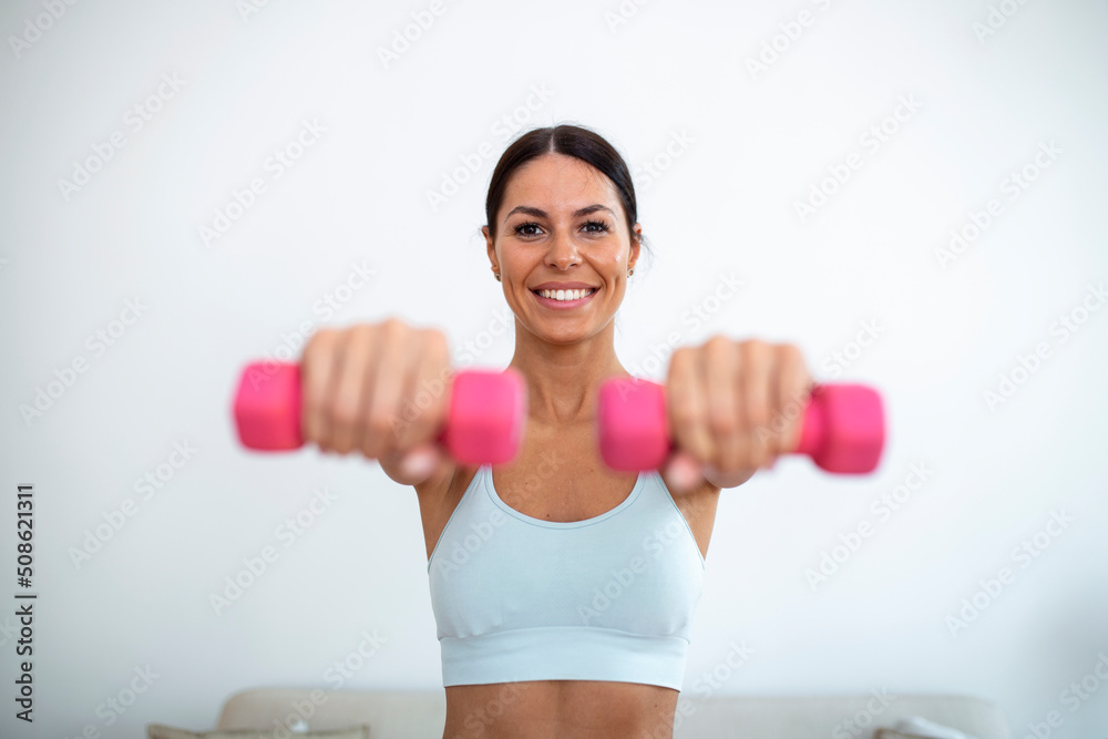 Woman exercising with dumbbells at home. Sporty beautiful woman exercising at home to stay fit. Woman exercising with dumbbells at home. Sporty beautiful woman exercising at home to stay fit.