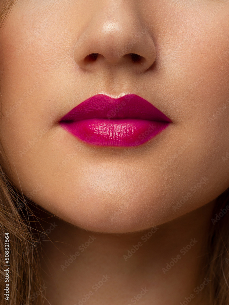 Fototapeta premium The macro photo of the closed female mouth. Chubby lips with pink lipstick show a fashionable make-up and increase in lips. Cosmetology, Spa, cosmetics
